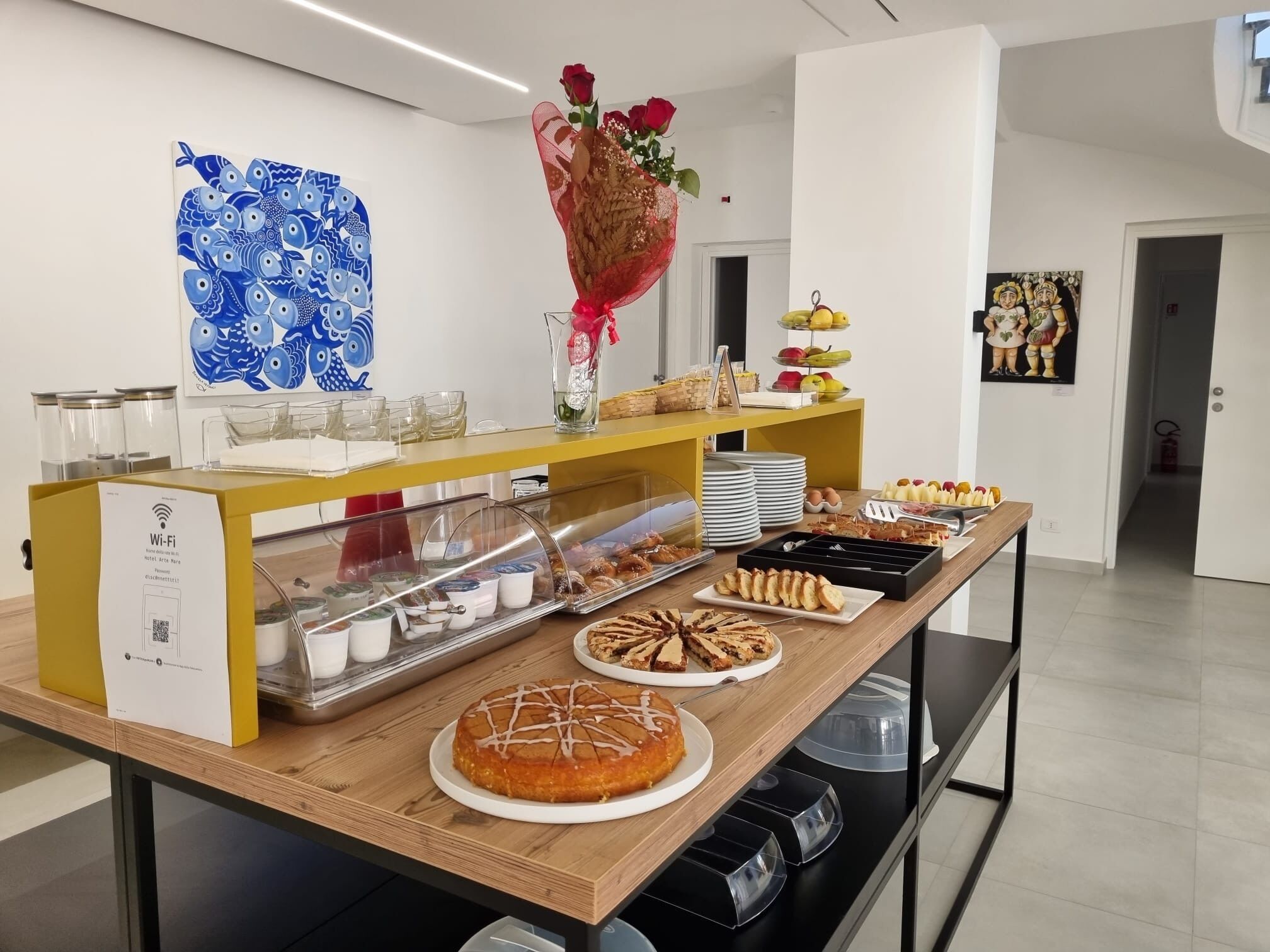 Een buffetopstelling met diverse gerechten, een Wi-Fi sign, en decoratieve elementen zoals een vaas met rozen en een blauw vispatroon aan de muur.
