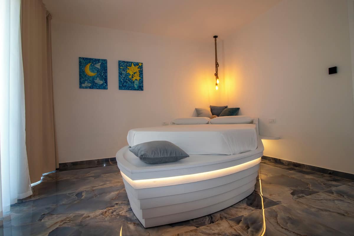 A modern bedroom with a curved bed, a nightlight, and two wall art pieces.