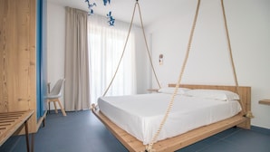 A modern bedroom with a wooden platform bed, a desk, and a chair. - Hotel Arte Mare (San Vito Lo Capo)