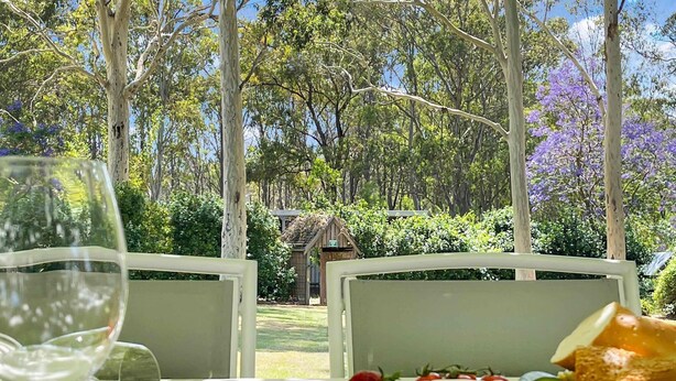An outdoor dining table with a variety of fruits and cheeses, surrounded by trees and a wooden structure in the background. - Alfie's Place - A period classic in central location (NULKABA)