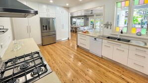 A modern kitchen with white cabinets, a stainless steel refrigerator, a gas stove, and a dishwasher. - Alfie's Place - A period classic in central location (NULKABA)