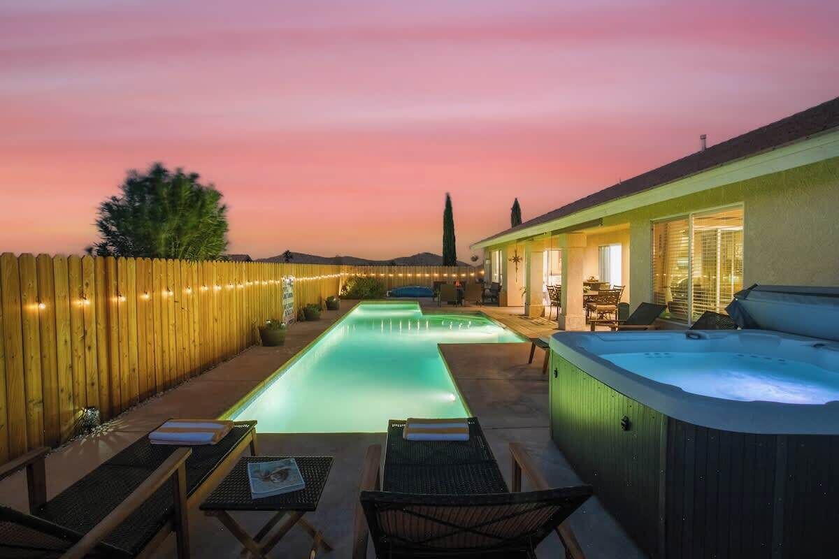 Un jardin avec une piscine, un jacuzzi et une clôture en bois.