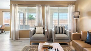 Un salon comprenant deux fauteuils, un canapé, une table basse avec un jeu d’échecs et une lampe.