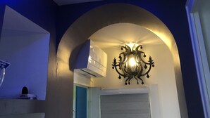 A room with a modern ceiling design featuring blue LED lighting, a decorative wall-mounted light fixture, and an air conditioning unit. - G1 Apartment with beautiful terrace between Grenoble and Chamrousse (Saint-Martin-d'Uriage)