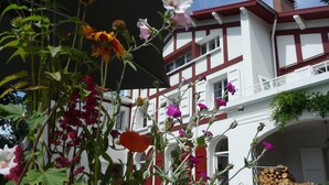 A building with a white facade and red trim, featuring multiple windows and balconies. - G1 Apartment with beautiful terrace between Grenoble and Chamrousse (Saint-Martin-d'Uriage)