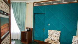 Una habitación con pared de acento color turquesa, un sofá floral, una mesita de madera y una mesa redonda pequeña.