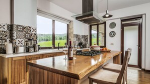 A modern kitchen with a large island, wooden cabinets, and a view of the outdoors.