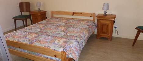Un dormitorio con una cama de madera, dos mesitas de noche, una silla y una lámpara.