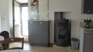 Une cuisine compacte dotée d’une cuisinière intégrée, d’une petite poubelle et d’un coin repas avec une table et des chaises.