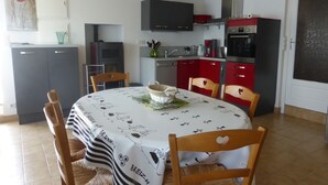 Un espace repas avec une table ronde, des chaises et une cuisine en arrière-plan.