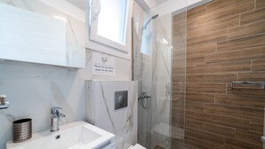 Ein modernes Badezimmer mit Marmorwaschtisch, Toilette und einer Duschkabine mit Holzboden.