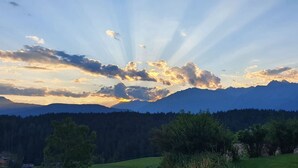 Paesaggio montuoso con una valle boscosa e cielo sereno.