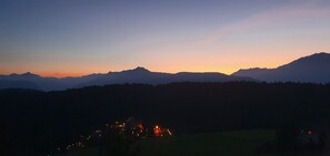 Un paysage montagneux au crépuscule, avec une ville au premier plan.