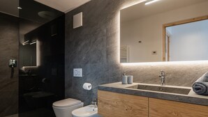 Un bagno moderno con bidet, water, mobile lavabo con specchio e asciugamano.