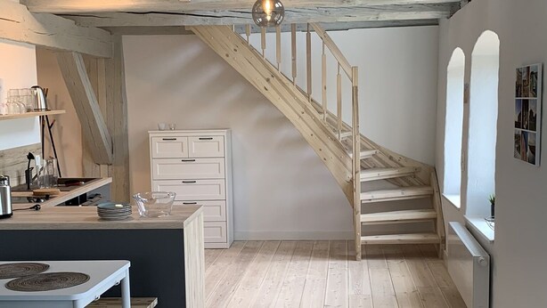 Ein modernes Loft mit freiliegenden Holzbalken, einer Treppe, einer Küchenzeile und einem Essbereich.