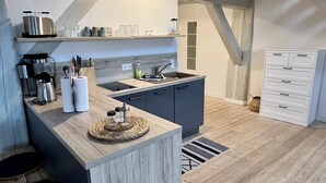Eine moderne Küche mit Holzbalken, einer eingebauten Kochinsel und einem weißen Schrank.