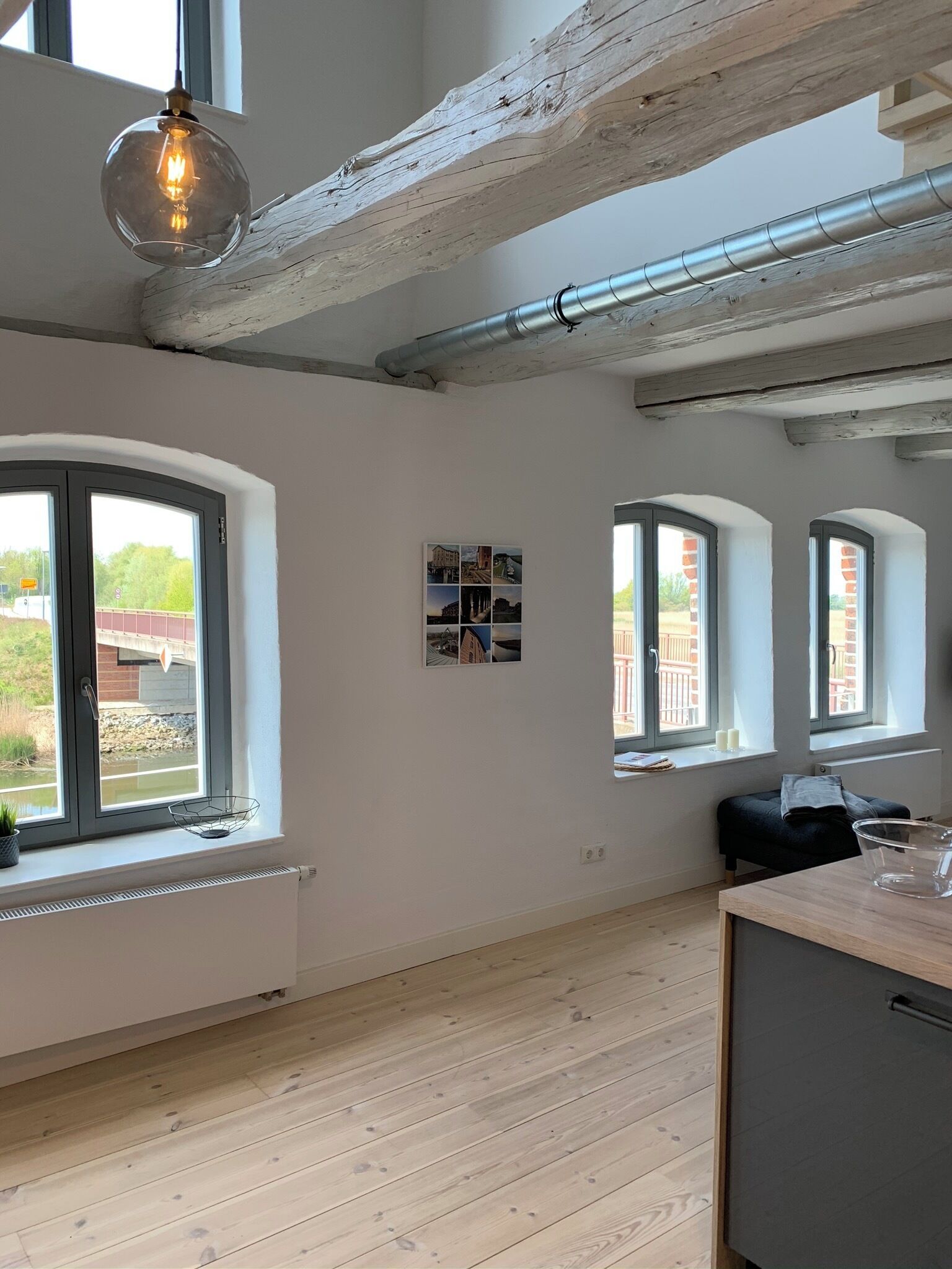 Ett rymligt rum med stora fönster, ett träpanelat tak och en modern lampa.