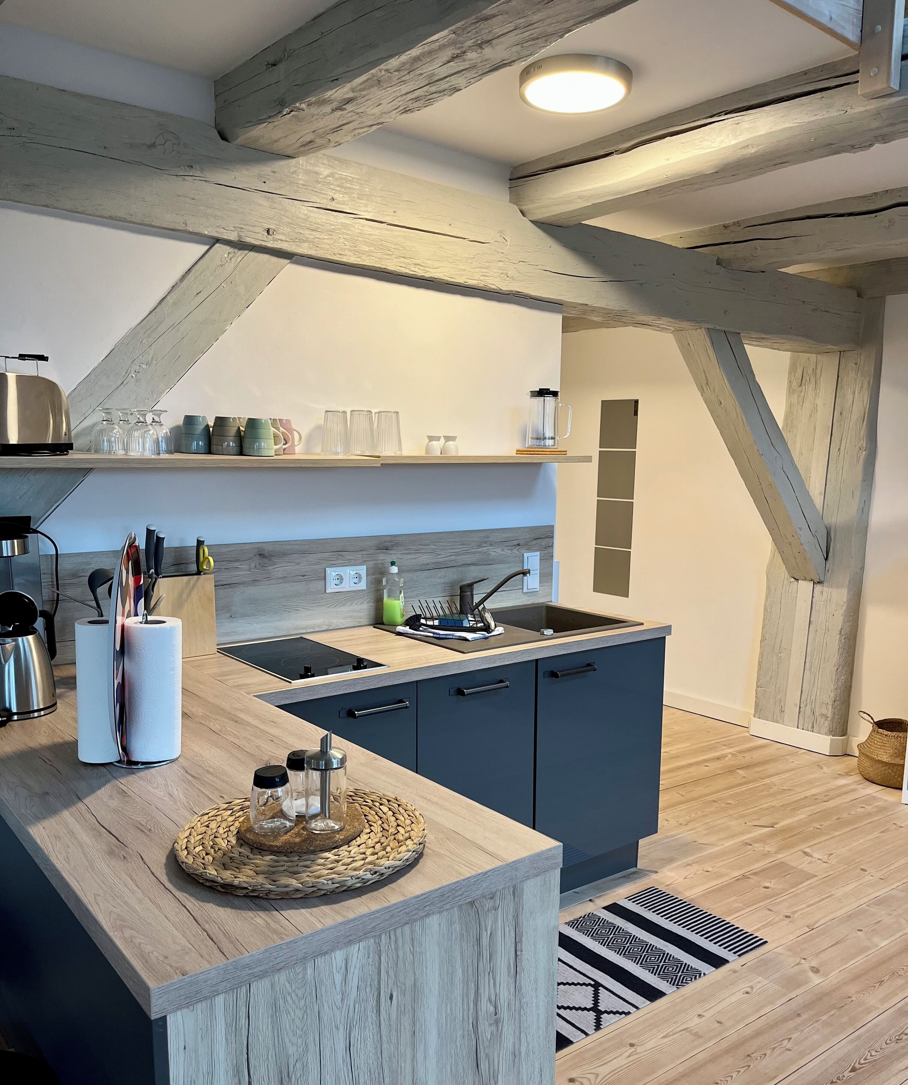 Una cocina moderna con una isla de madera, electrodomésticos integrados y una lámpara colgante.