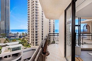 A balcony with a view of the ocean and high-rise buildings.