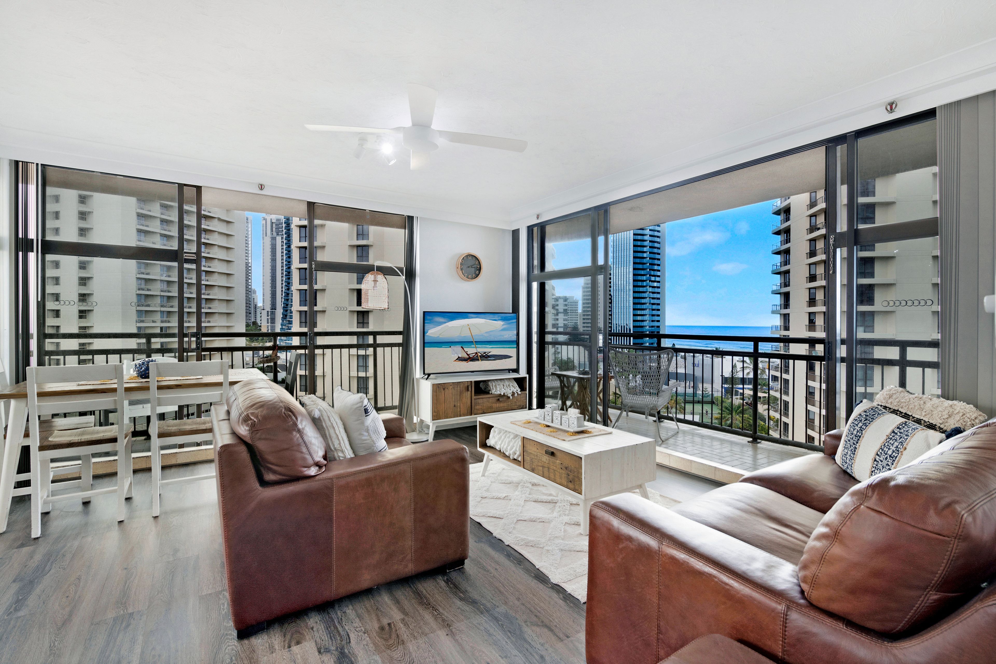 A spacious living area with a large window overlooking a cityscape and the sea.