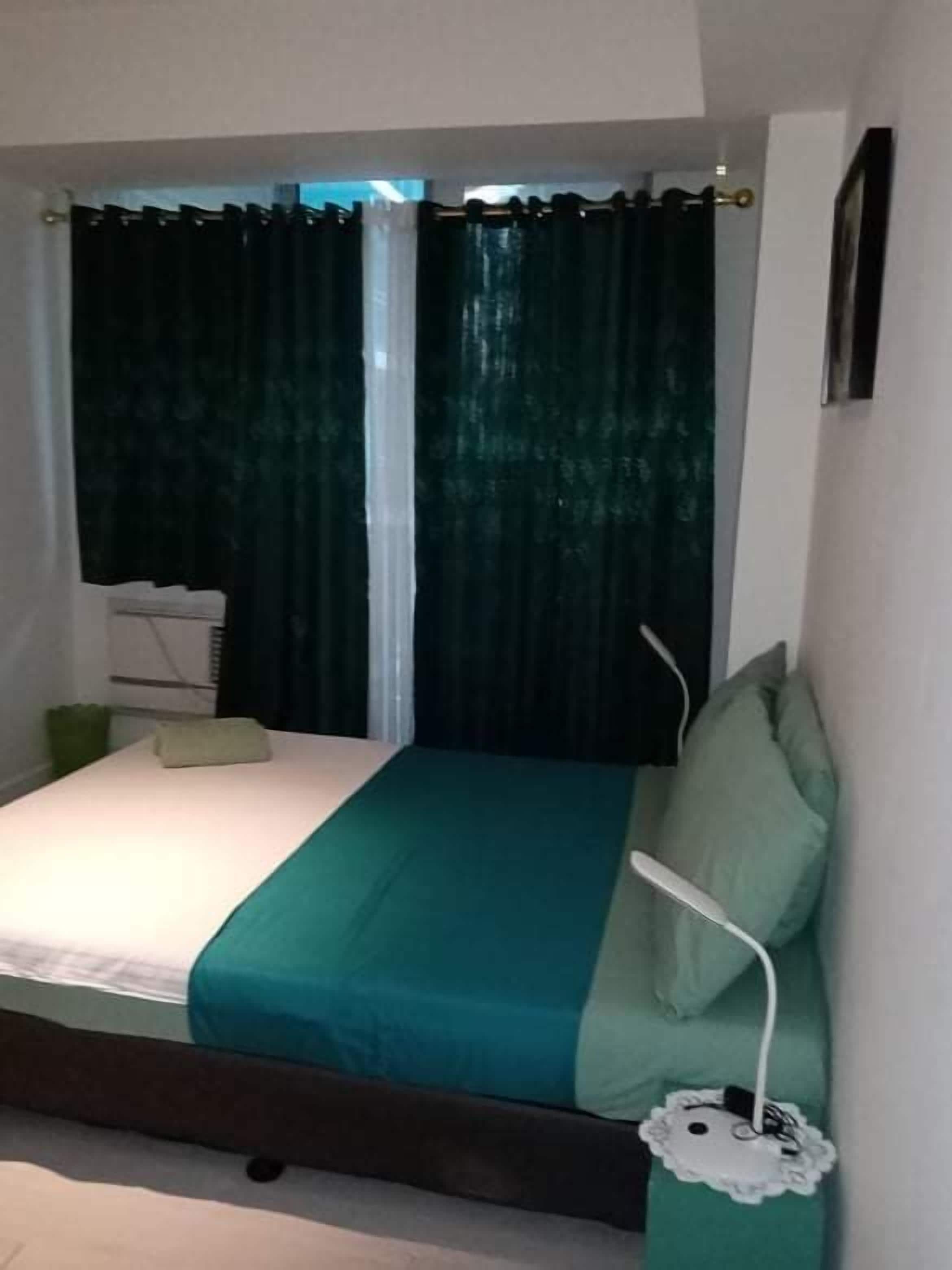 Ein Schlafzimmer mit Bett, Vorhängen, Nachttisch und Lampe.