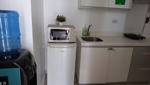 A compact kitchen with a microwave, sink, and a water dispenser. - Azure Condotel  (Parañaque)