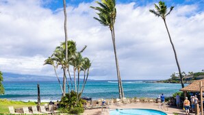 A poolside area with lounge chairs, palm trees, and a view of the ocean. - Napili Shores A202 Of Studio 1 Bedroom Condo by RedAwning (Lahaina)