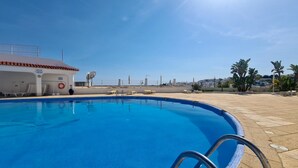 A clear blue pool with a lifebuoy, lounge chairs, and a building with a tiled roof. - Albufeira Modern Sea View Home 33 (Albufeira)