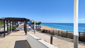 A coastal promenade with a beach, a covered seating area, and a hotel named "Feria Hotel" in the background. - Albufeira Modern Sea View Home 33 (Albufeira)