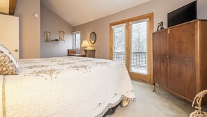 A bedroom with a large bed, a wooden wardrobe, a desk with a lamp, and a window with blinds. - Beary Relaxing by Taylor Made Deep Creek (McHenry)