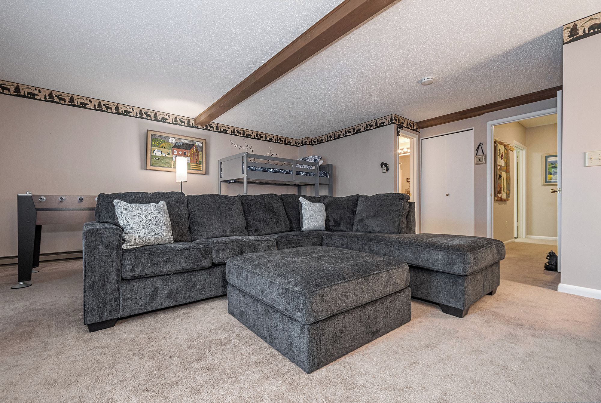 A living room with a sectional sofa, a bunk bed, and a framed picture on the wall.