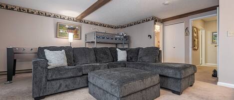 A living room with a sectional sofa, a bunk bed, and a framed picture on the wall.