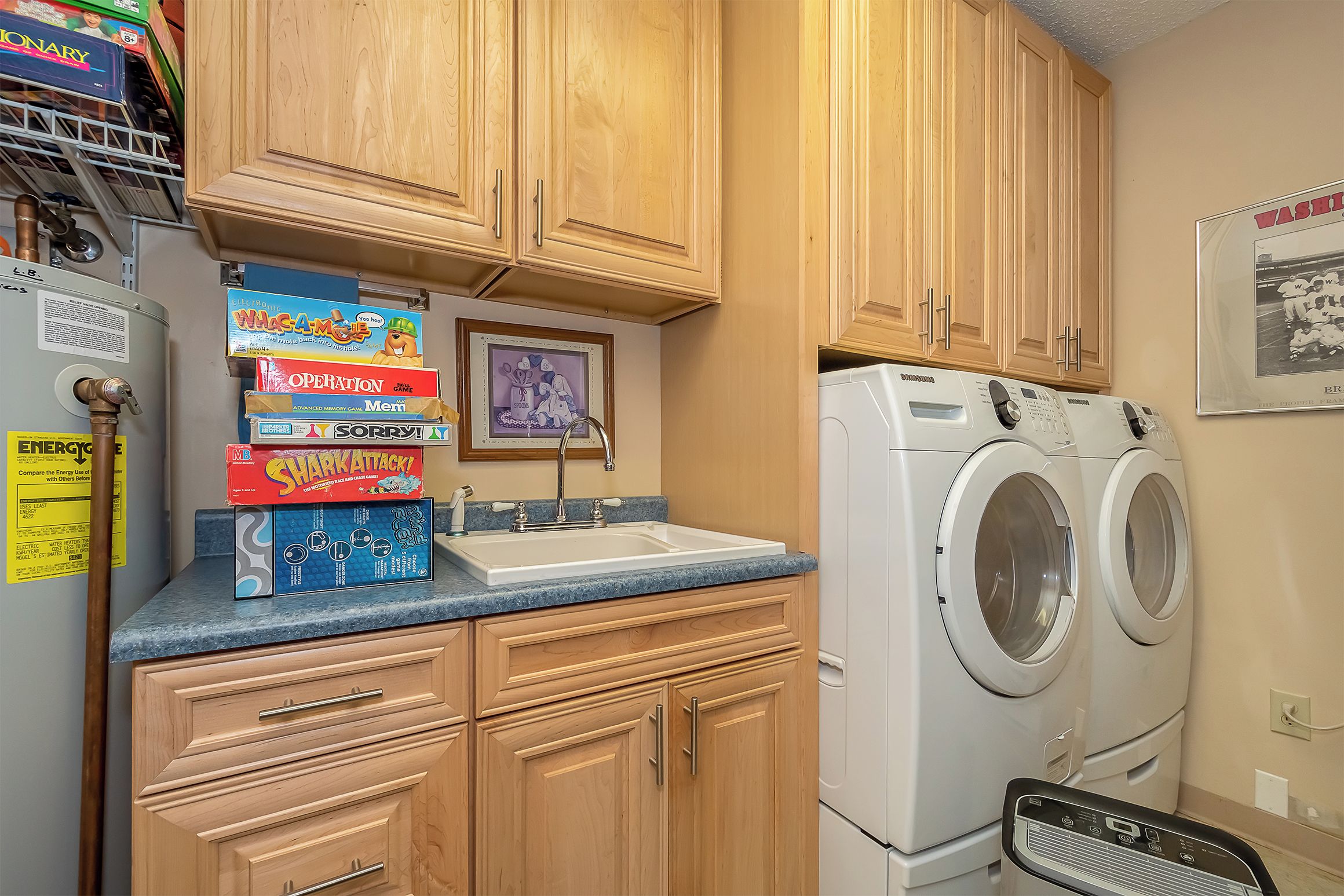 A laundry area with wooden cabinets, a sink, and a washing machine.
