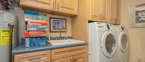 A laundry area with wooden cabinets, a sink, and a washing machine.