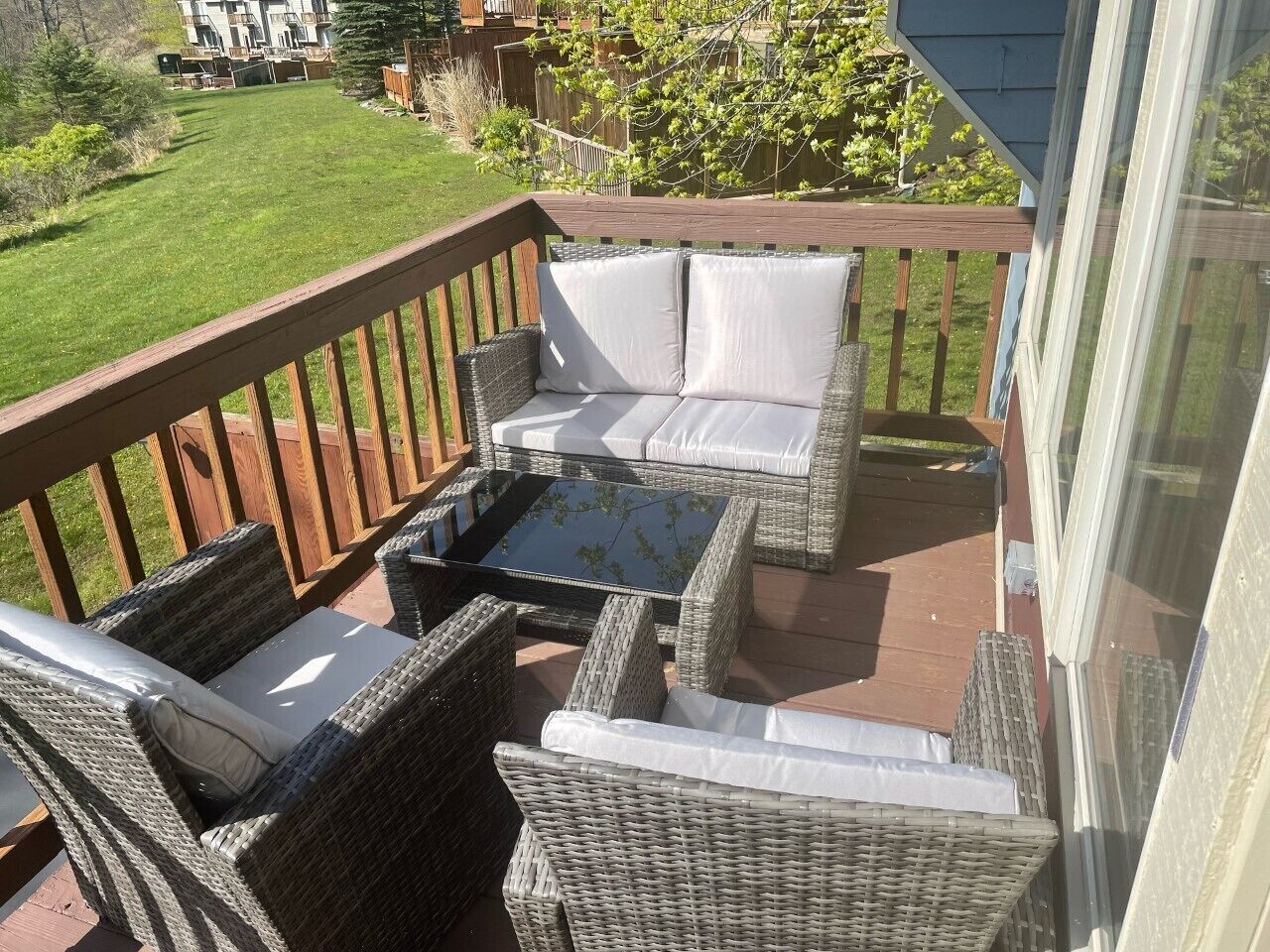 A balcony with wicker furniture, including a sofa and chairs, and a glass coffee table.