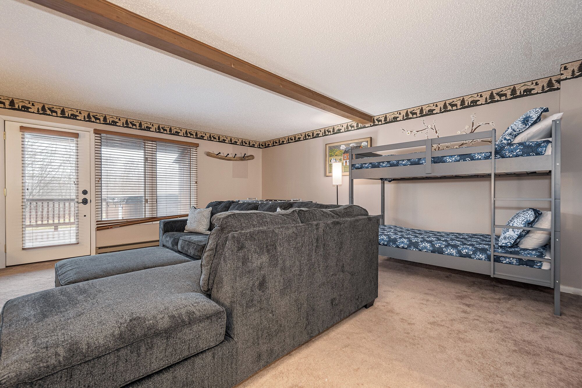 Ein Zimmer mit einem Etagenbett, einer Schlafcouch und einer Tür mit Jalousien.