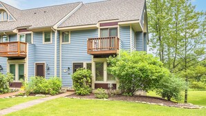 A two-story residential building with a balcony on the second floor, a well-maintained lawn, and mature trees. - Beary Relaxing by Taylor Made Deep Creek (McHenry)