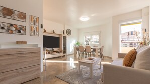 A modern living room with a flat-screen TV, a sofa, a coffee table, and a dining area with chairs and a table. - Holiday Apartment "Palma De Mallorca 12" with Private Terrace, A/C & Wi-Fi (Torremolinos)