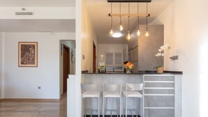 A modern kitchen with a bar area, white bar stools, and pendant lighting. - Holiday Apartment "Palma De Mallorca 12" with Private Terrace, A/C & Wi-Fi (Torremolinos)