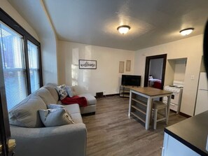 Ein gemütlicher Wohnbereich mit Sofa, Fernseher, Esstisch und Küchenzeile.