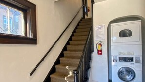 Una escalera con peldaños alfombrados, barandilla e extintor en la pared.