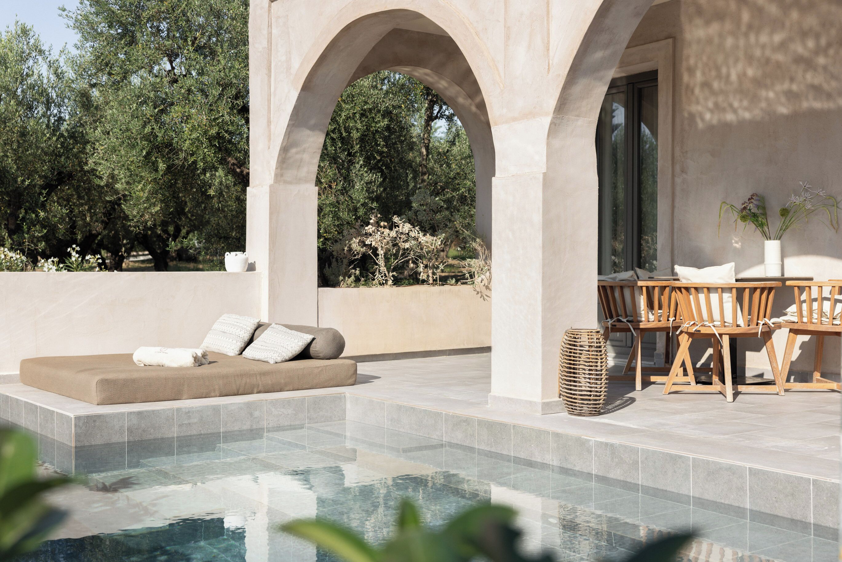 A poolside area with a seating arrangement, a table, and a potted plant.