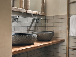 A bathroom with a wooden vanity, two stone sinks, a mirror, and a towel rack. - casa di pierro (Zakynthos)