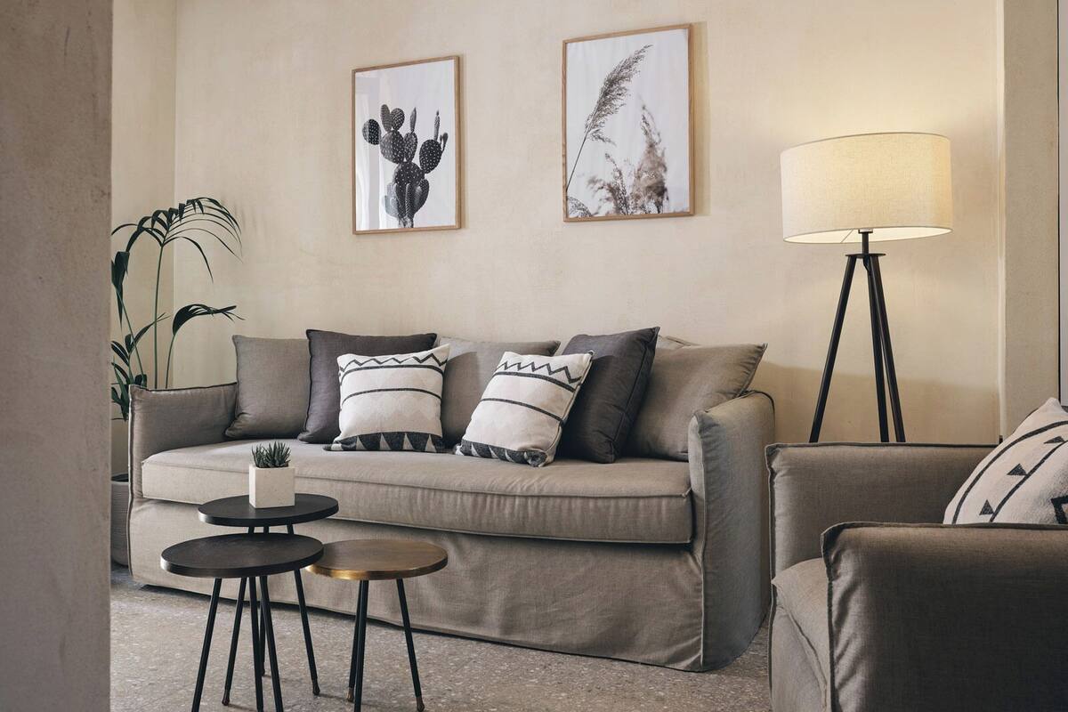 A living room with a sofa, two side tables, a floor lamp, and two framed pictures on the wall.