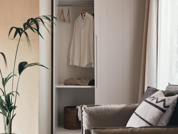 A room with a white wardrobe, a plant, and a sofa with cushions. - casa di pierro (Zakynthos)