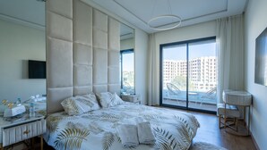 Een moderne hotelkamer met een groot bed, een bureau met een flatscreen-televisie, een raam met uitzicht op de stad en een balkon.