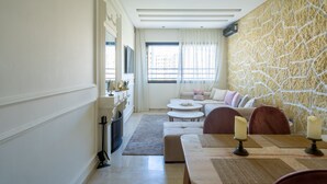 Een moderne woonkamer met een stenen muur, een zithoek, een eettafel en een open haard.