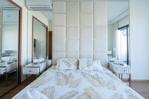 Una habitación de hotel moderna con una cama grande, un espejo, un tocador y una ventana.