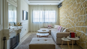 Een woonkamer met een open haard, een bank, twee salontafels en een wand met een stenen patroon.