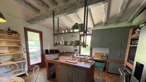 A rustic kitchen with a central island, wooden flooring, and exposed beams.